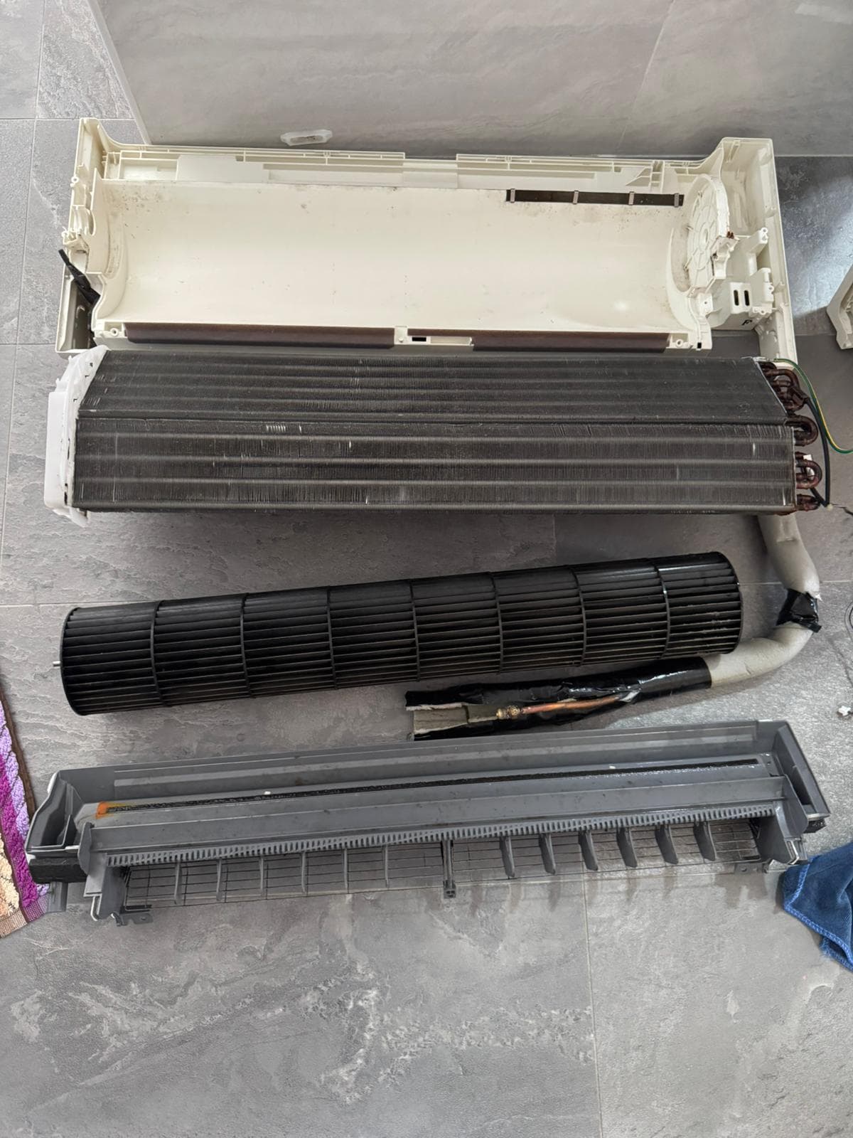 Aircon unit fully disassembled during chemical overhaul, showing housing, coil, blower wheel, and drain tray